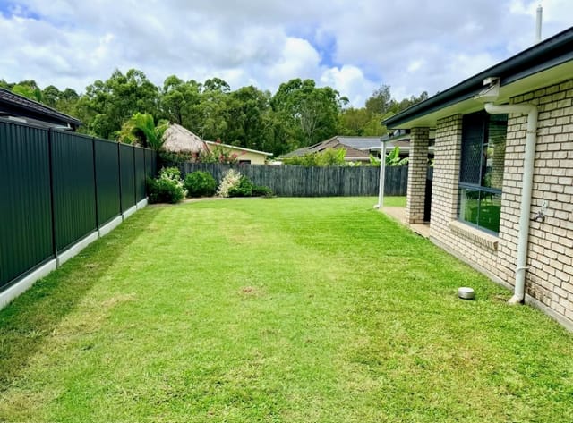 A green lawn bordered by a Colorbond fence and garden beds